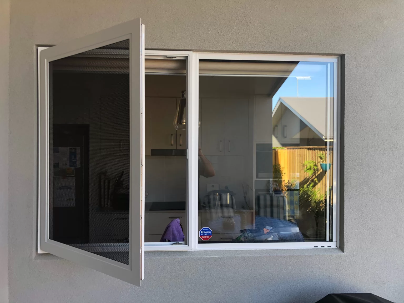 Hinged security window screen installed on a residential home